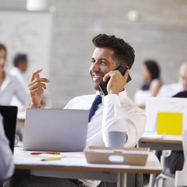 Businessman Using Mobile Phone In Busy Office